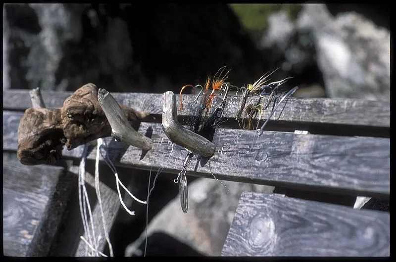 Flies in the bench - A bunch of old flies, lures and hooks are stuck in a bench as a testemony of the season almost gone.